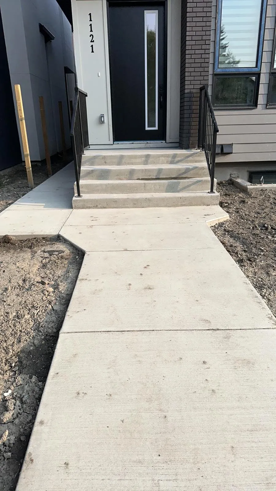 Newly poured four-step concrete front entry with railings on a new-construction Calgary home