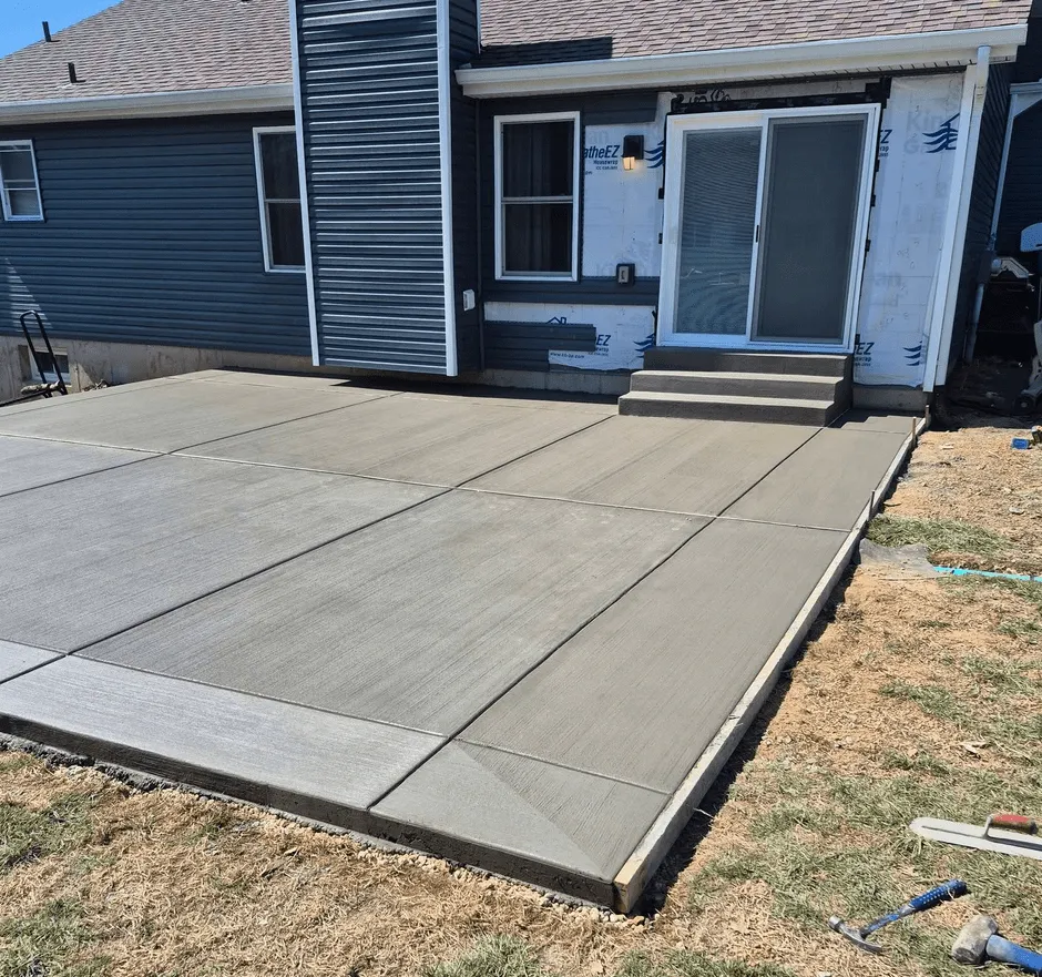 Finished broom-finish concrete patio with steps up to a sliding door on a Calgary home