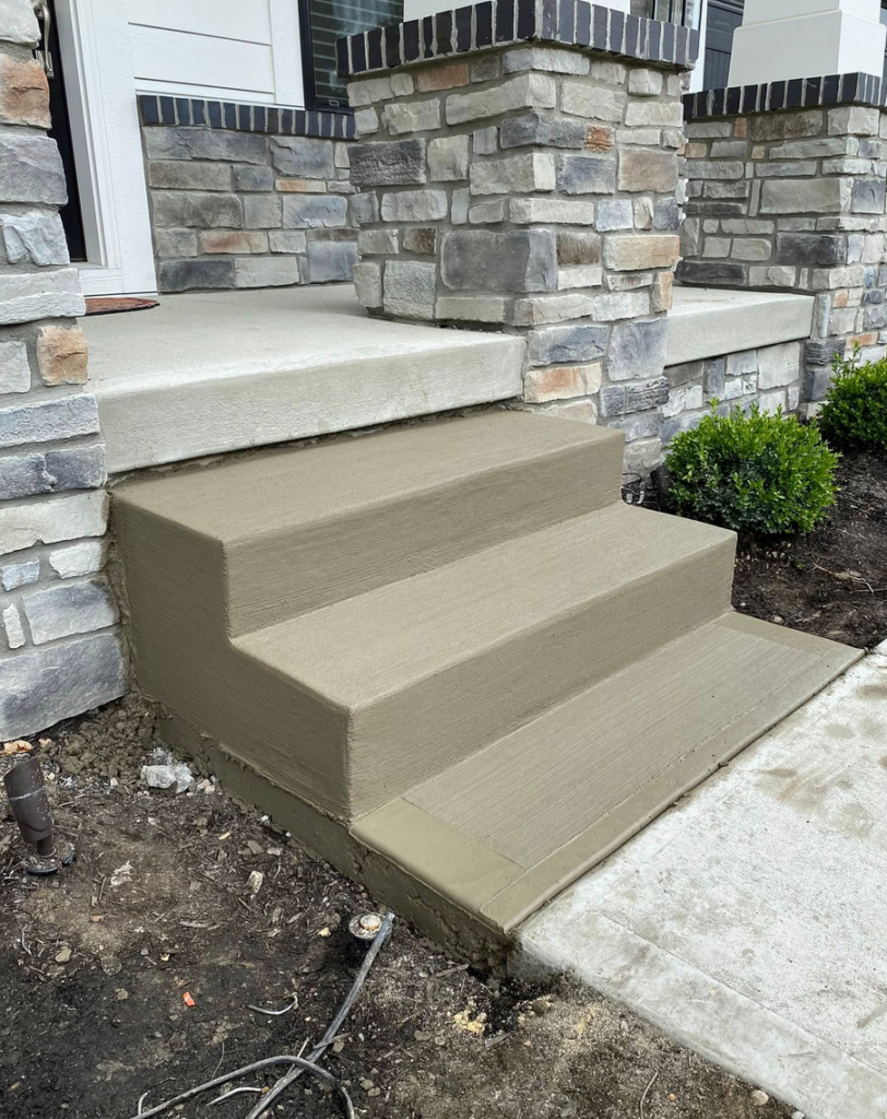 Concrete front entry steps with broom finish next to stone veneer columns in Calgary by Concrete Star