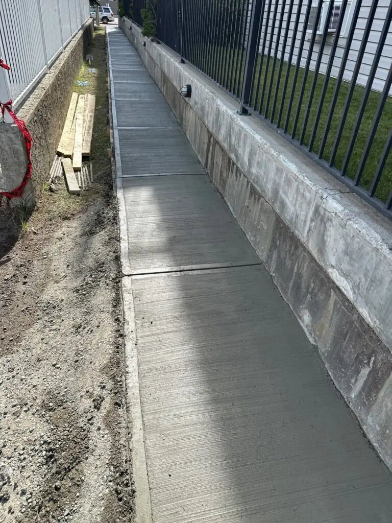 new-sidewalk-retaining-wall-fence New concrete sidewalk joined to retaining wall with rebar anchors at 15304 Bannister Rd SE, Calgary, AB T2X 3R6