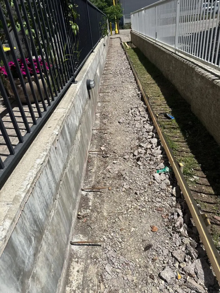 rebar-anchors-between-railings Rebar anchors drilled into retaining wall between railings before concrete sidewalk pour at Bannister Rd SE in Calgary, AB